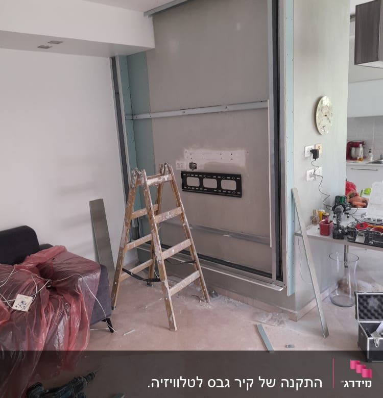 קיר גבס בבנייה עם סולם וכלי עבודה